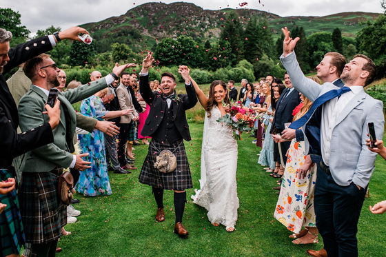 Bride and groom celebrate as they walk back down aisle through confetti thrown by their loved ones